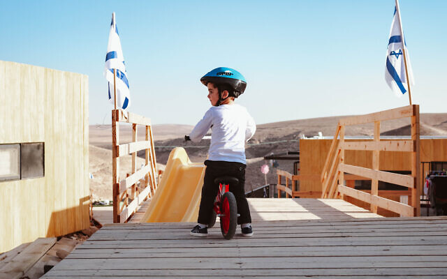 Un enfant sur un vélo  dans le quartier temporaire de Shahak Heights à Dimona, dans le sud d'Israël, le21 décembre 2020. (Crédit : Sue Surkes/Times of Israel)