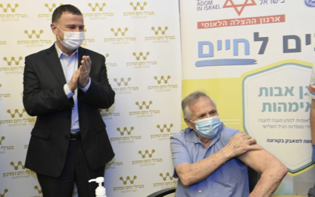 Yuli Edelstein applaudit alors qu'un homme est vacciné dans un centre de soins pour personnes âgées à Shaarei Tikva, le 22 décembre 2020. (Ministère de la Santé)