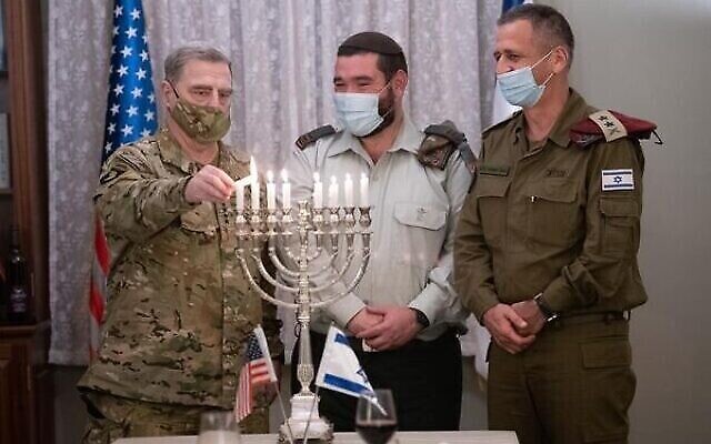 Le président des chefs d'état-major interarmées des États-Unis, le général Mark Milley, allume une menorah le huitième soir de la fête de Hanoukka aux côtés du Cpt. Josh Gerstein et du chef d'état-major de Tsahal, Aviv Kohavi, au quartier général de l'armée à Tel Aviv, le 17 décembre 2020. (Crédit : Armée de défense d’Israël)