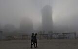Deux piétons marchent sur la plage tôt le 6 janvier 2021, dans la ville côtière de Netanya, au milieu du brouillard matinal lors de la première semaine de la nouvelle année. (JACK GUEZ / AFP)
