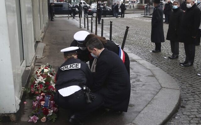 Le ministre français de l'Intérieur Gérald Darmanin et la maire de Paris Anne Hidalgo déposent une gerbe de fleurs devant le supermarché casher "Hyper Cacher", le 7 janvier 2021, à Paris, lors d'une cérémonie marquant le sixième anniversaire de l'attaque jihadiste contre le magazine satirique "Charlie Hebdo" et le commerce juif. (Crédit : Michel Euler / POOL / AFP)