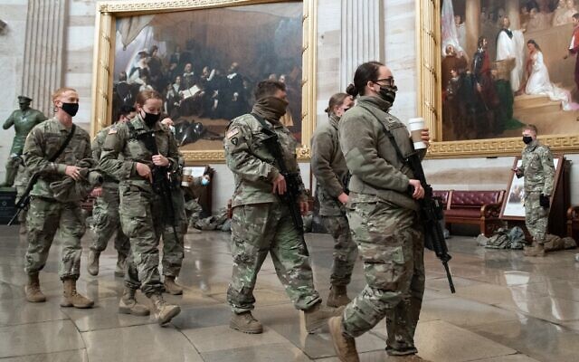 Des membres de la Garde nationale marchent dans la rotonde du Capitole américain à Washington, DC, le 13 janvier 2021, avant le vote de la Chambre des représentants mettant en accusation le président américain Donald Trump. (Saul Loeb / AFP)