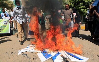 Des manifestants soudanais brûlent des drapeaux israéliens pendant un rassemblement suite à la signature d'un accord de normalisation entre le Soudan et l'Etat juif aux abords des bureaux du cabinet à Khartoum, le 17 janvier 2021. (Crédit :  ASHRAF SHAZLY / AFP)