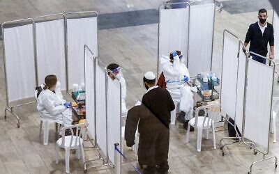Un voyageur s'adresse à un médecin pour qu'il lui fasse passer un test de dépistage du coronavirus, à son arrivée au centre de dépistage rapide de l'aéroport international Ben-Gurion, près de Tel-Aviv, le 24 janvier 2021. (Crédit : JACK GUEZ / AFP)