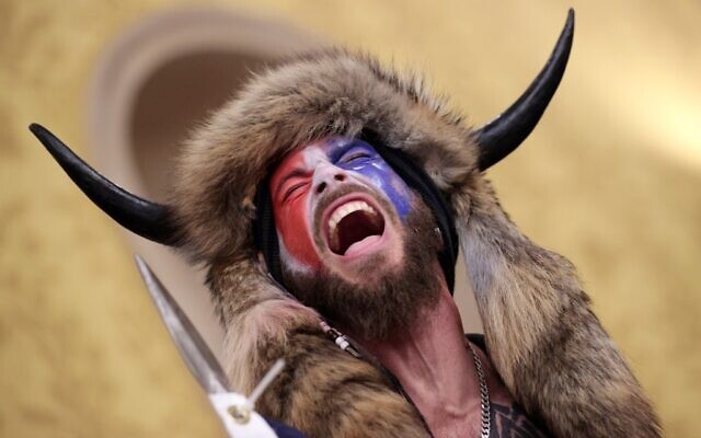 Jake Angeli, un partisan de Qanon connu pour ses peintures au visage et son chapeau à cornes, au Capitole américain le 6 janvier 2021 à Washington, DC (Crédit : SAUL LOEB / AFP) Jake Angeli, un partisan de Qanon connu pour ses peintures au visage et son chapeau à cornes, au Capitole américain le 6 janvier 2021 à Washington, DC (Crédit : SAUL LOEB / AFP)