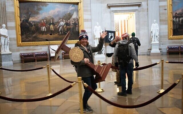 Un manifestant pro-Trump porte le lutrin de la Présidente de la Chambre des représentants des Etats-Unis, Nancy Pelosi, à travers la Rotonde du Capitole américain après qu'une foule pro-Trump ait pris d'assaut le bâtiment le 6 janvier 2021 à Washington, DC. (Crédit : Gagner McNamee/Getty Images/AFP) Un manifestant pro-Trump porte le lutrin de la Présidente de la Chambre des représentants des Etats-Unis, Nancy Pelosi, à travers la Rotonde du Capitole américain après qu'une foule pro-Trump ait pris d'assaut le bâtiment le 6 janvier 2021 à Washington, DC. (Crédit : Gagner McNamee/Getty Images/AFP)