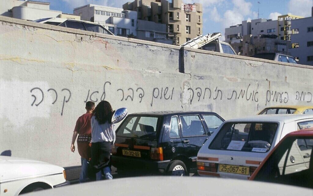 Des Israéliens devant des graffitis indiquant : "Combien de fois avez-vous scellé la pièce, et rien ne s'est passé ?", en référence à la chanson de Rafi Persky, à propos des attaques de missiles Scud contre Israël pendant la première guerre du Golfe de 1991, craints par les Israéliens car ils auraient pu transporter des armes chimiques ou biologiques. (Alex Lebac / Archives du ministère de la Défense)