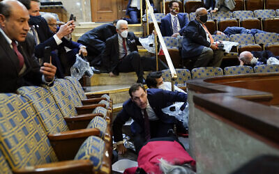 Des gens s'abritent dans la galerie de la Chambre des représentants alors que des manifestants tentent de s'introduire dans l'hémicycle du Capitole américain, le mercredi 6 janvier 2021, à Washington. (AP Photo/Andrew Harnik)