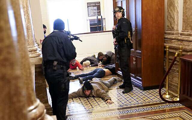 La police du Capitole américain tient des manifestants sous la menace d'une arme à feu près de la Chambre des représentants, à l'intérieur du Capitole américain, le mercredi 6 janvier 2021, à Washington. (Crédit : AP Photo/Andrew Harnik) La police du Capitole américain tient des manifestants sous la menace d'une arme à feu près de la Chambre des représentants, à l'intérieur du Capitole américain, le mercredi 6 janvier 2021, à Washington. (Crédit : AP Photo/Andrew Harnik)