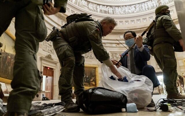 Le représentant Andy Kim, D-N.J., aide la police à nettoyer les débris et les effets personnels éparpillés sur le sol de la rotonde aux petites heures du matin le jeudi 7 janvier 2021, après que des manifestants ont pris d'assaut le Capitole à Washington, la veille. (Crédit : AP Photo/Andrew Harnik)