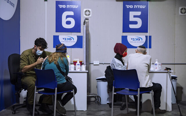 Une femme reçoit son deuxième vaccin Pfizer-BioNTech COVID-19 par un médecin de l'armée, (à gauche), dans un centre de vaccination installé sur le parking d'un centre commercial à Givataim, dans le centre d'Israël, au cours d'un confinement national visant à enrayer la propagation du virus, le 20 janvier 2021. (AP Photo/Oded Balilty) Une femme reçoit son deuxième vaccin Pfizer-BioNTech COVID-19 par un médecin de l'armée, (à gauche), dans un centre de vaccination installé sur le parking d'un centre commercial à Givataim, dans le centre d'Israël, au cours d'un confinement national visant à enrayer la propagation du virus, le 20 janvier 2021. (AP Photo/Oded Balilty)