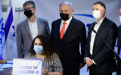 Le Premier ministre Benjamin Netanyahu (C) et le ministre de la Santé Yuli Edelstein (D) dans une clinique des services de santé Maccabi dans la ville centrale de Ramle, alors qu'une enseignante devient le 2 millionième Israélien à être vacciné contre la COVID-19, le 14 janvier 2021. (Tomer Neuberg / Flash90)