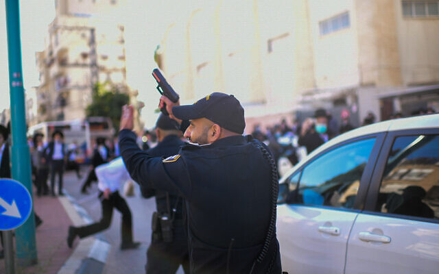Un policier pointe son arme en l'air lors d'un affrontement avec des émeutiers ultra-orthodoxes qui protestaient contre l'application d'un confinement ordonné en raison du coronavirus, dans la ville de Bnei Brak, le 24 janvier 2021. (Tomer Neuberg/Flash90) Un policier pointe son arme en l'air lors d'un affrontement avec des émeutiers ultra-orthodoxes qui protestaient contre l'application d'un confinement ordonné en raison du coronavirus, dans la ville de Bnei Brak, le 24 janvier 2021. (Tomer Neuberg/Flash90)