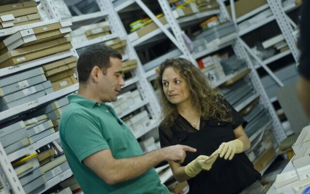 Le docteur Erez Ben-Yosef et la docteure  Naama Sukenik examinent des fragments de textile colorés découverts à Timna. (Crédit : Yolli Schwartz, autorisation de l'Autorité israélienne des antiquités)