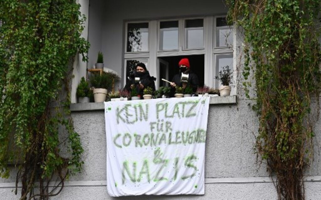 Des contre-manifestants crient depuis leur balcon où une banderole portant l'inscription "Pas de place pour les négationnistes et les nazis" est fixée lors d'une marche silencieuse contre les mesures visant à freiner la propagation du coronavirus à Berlin, le 22 novembre 2020. (Tobias Schwarz / AFP)