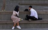 Un Juif ultra-orthodoxe et une femme discutent sur un banc sur une place du centre de Jérusalem, le 27 janvier 2021. (Crédit : MENAHEM KAHANA / AFP)
