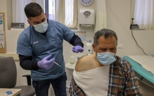 Un employé du secteur de la santé administre une dose de vaccin contre la COVID-19 Pfizer-BioNtech à Jérusalem-Est, le 3 février 2021. (Crédit : AHMAD GHARABLI / AFP)