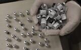 Un soignant tient des flacons vides du vaccin COVID-19 de Pfizer-BioNtech dans une clinique de Jérusalem-Est le 3 février 2021. (Crédit ; AHMAD GHARABLI / AFP)