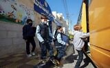 Des élèves jordaniens montent dans un bus pour rentrer chez eux après avoir assisté à un cours pour la première fois depuis près d'un an, à Amman, le 7 février 2021. (Crédit : Khalil MAZRAAWI / AFP)