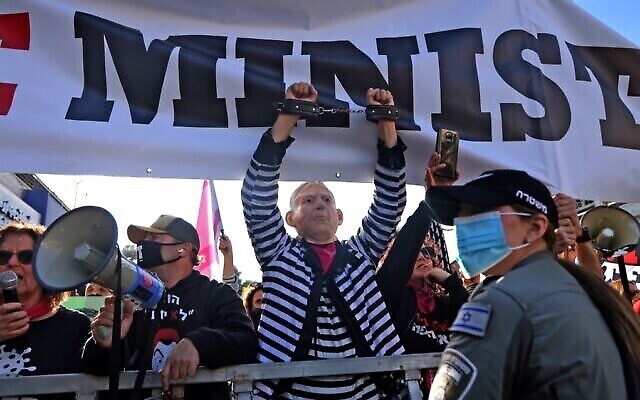 Des manifestants anti-Netanyahu devant le tribunal de district de Jérusalem, alors que le Premier ministre Benjamin Netanyahu arrive pour son procès au tribunal de district, le 08 février 2021 (Crédit : Emmanuel DUNAND/AFP)