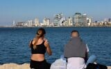 Un jeune couple devant la skyline de Tel Aviv, le 15 février 2021. (Crédit : Emmanuel DUNAND / AFP)