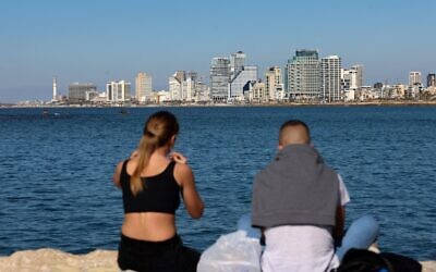 Un jeune couple devant la skyline de Tel Aviv, le 15 février 2021. (Crédit : Emmanuel DUNAND / AFP)