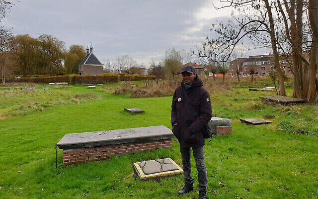 Sergio Berrenstein à côté de la tombe d'Elieser et de celle de son maître à l'entrée du cimetière juif d'Ouderkerk aan de Amstel, aux Pays-Bas, le 20 novembre 2020. (Autorisation : Cnaan Liphshiz/ JTA)