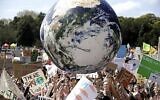Un grand globe gonflable est projeté dans la foule alors que des milliers de manifestants, dont beaucoup d'écoliers, se rassemblent à Sydney, le 20 septembre 2019, pour appeler à l'action afin de se prémunir contre le changement climatique. (AP Photo/Rick Rycroft)