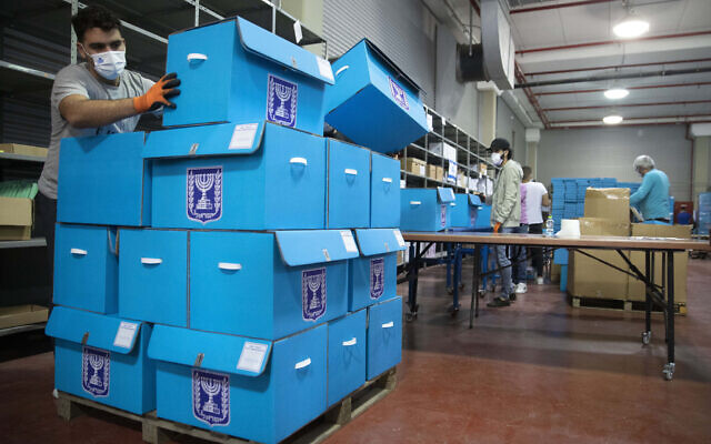 Des employés préparent des urnes pour les prochaines élections durant une visite des médias dans le centre de logistique électorale de Shoham, en Israël, le 23 février 2021. (Crédit : AP Photo/Sebastian Scheiner) Des employés préparent des urnes pour les prochaines élections durant une visite des médias dans le centre de logistique électorale de Shoham, en Israël, le 23 février 2021. (Crédit : AP Photo/Sebastian Scheiner)