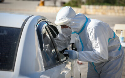 Des techniciens médicaux dépistent des Israéliens au coronavirus sur un site de type-drive-in dans la ville de Tzfat, dans le nord du pays, le 1er février 2021. (Crédit : David Cohen/Flash90)