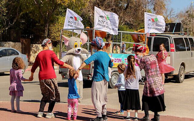 Des Israéliens en costume dansent  avant la fête de Pourim à Efrat, à Gush Etzion, le 12 février 2021. (Crédit : Gershon Elinson/Flash90)