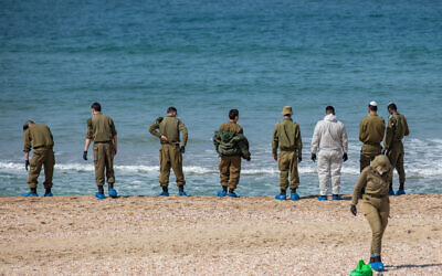Des soldats israéliens nettoient le goudron sur la plage de Palmachim à la suite d'une marée noire en mer, qui a recouvert la plus grande partie du littoral israélien, le 22 février 2021. (Yonatan Sindel/Flash90 *** Local Caption)
