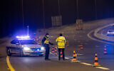 La police met au point un barrage routier temporaire sur la Route 1, près de Jérusalem, pendant un couvre-feu nocturne pour la fête de Pourim, le 25 février 2021. (Crédit : Yonatan Sindel/Flash90)