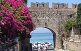 Des touristes se promenant le long des vieux murs de la ville de Rhodes, près de la place des Martyrs juifs. (Crédit : Gavin Rabinowitz/JTA)