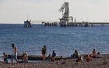 Des Israéliens sur une plage de la mer Morte, à proximité du Terminal pétrolier de l'EAPC (Eilat-Ashkelon Pipeline) dans la ville portuaire d'Eilat, dans le sud du pays, le 10 février 2021. (Crédit : Menahem Kahana / AFP)