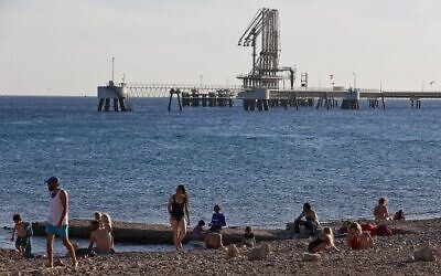 Des Israéliens sur une plage de la mer Morte, à proximité du Terminal pétrolier de l'EAPC (Eilat-Ashkelon Pipeline) dans la ville portuaire d'Eilat, dans le sud du pays, le 10 février 2021. (Crédit : Menahem Kahana / AFP)