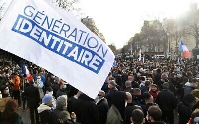Des membres et partisans du groupe d'extrême droite Génération identitaire et un drapeau du mouvement lors d'une manifestation contre sa possible dissolution, à Paris, le 20 février 2021. (Crédit : Bertrand GUAY / AFP)