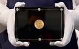 Un employé de Sotheby's porte une pièce de monnaie Double Eagle de 1933 à l’occasion de la vente aux enchères « Trois trésors - Collectés par Stuart Weitzman », dédiée aux trois trésors de la collection personnelle du créateur de mode et collectionneur, chez Sotheby’s, le 11 mars 2021, à New York. (Crédit : Angela Weiss / AFP)