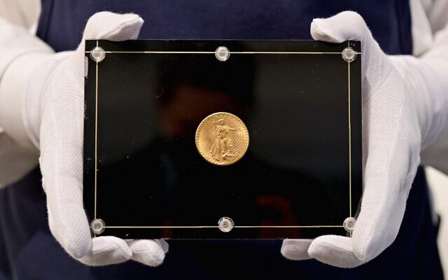 Un employé de Sotheby's porte une pièce de monnaie Double Eagle de 1933 à l’occasion de la vente aux enchères « Trois trésors - Collectés par Stuart Weitzman », dédiée aux trois trésors de la collection personnelle du créateur de mode et collectionneur, chez Sotheby’s, le 11 mars 2021, à New York. (Crédit : Angela Weiss / AFP) Un employé de Sotheby's porte une pièce de monnaie Double Eagle de 1933 à l’occasion de la vente aux enchères « Trois trésors - Collectés par Stuart Weitzman », dédiée aux trois trésors de la collection personnelle du créateur de mode et collectionneur, chez Sotheby’s, le 11 mars 2021, à New York. (Crédit : Angela Weiss / AFP)