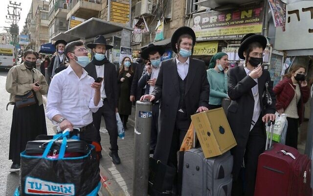 Des Israéliens attendent à un arrêt de bus du quartier ultra-orthodoxe de Méa Shéarim, à Jérusalem, le 11 mars 2021. (Crédit : MENAHEM KAHANA / AFP) Des Israéliens attendent à un arrêt de bus du quartier ultra-orthodoxe de Méa Shéarim, à Jérusalem, le 11 mars 2021. (Crédit : MENAHEM KAHANA / AFP)