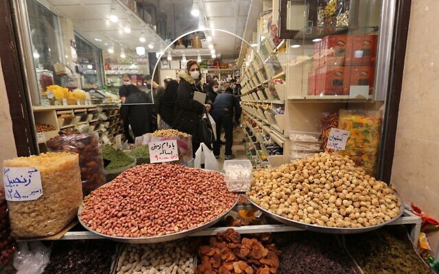 Des Iraniens masqués font des achats en pleine pandémie de Covid-19, au Bazar Tajrish à Téhéran, le 17 mars 2021, alors que l'Iran se prépare à célébrer Nowruz, le nouvel an iranien. (Crédit ATTA KENARE / AFP)