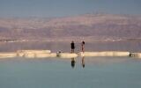 Un couple marche sur un îlot de sel formé sur la mer Morte dans la station balnéaire israélienne d'Ein Bokek, le 27 mars 2021. (Crédit : Emmanuel DUNAND / AFP)