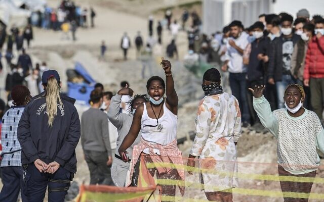 Des femmes migrantes africaines crient « liberté » à l'intérieur du nouveau camp de réfugiés de Kara Tepe à Mytilène, à Lesbos, le 29 mars 2021. (Crédit : ARIS MESSINIS / AFP)