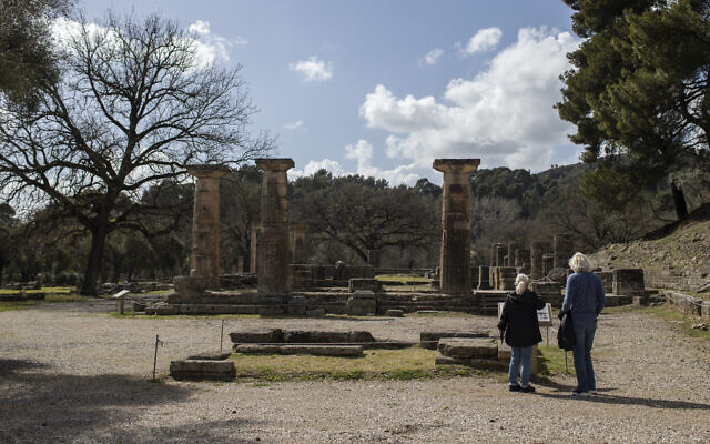 Des touristes devant le temple d'Héra dans l'ancienne Olympie, lieu qui a accueilli les Jeux Olympiques antiques, le lundi 22 mars 2021. (Photo AP / Petros Giannakouris) Des touristes devant le temple d'Héra dans l'ancienne Olympie, lieu qui a accueilli les Jeux Olympiques antiques, le lundi 22 mars 2021. (Photo AP / Petros Giannakouris)