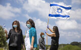 Des personnels médicaux et des malades, portant des masques, brandissent des drapeaux israéliens alors que les forces aériennes font une démonstration de vol acrobatique au dessus de l'hôpital Hillel Yaffe à Hadera, dans le nord d'Israël, le 29 avril 2020. (Crédit ;Ariel Schalit/AP)