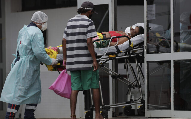 Des soignants reçoivent un patient soupçonné d'avoir le COVID-19 à l'hôpital public HRAN de Brasilia, au Brésil, le 8 mars 2021. (Crédit : Eraldo Peres/AP) Des soignants reçoivent un patient soupçonné d'avoir le COVID-19 à l'hôpital public HRAN de Brasilia, au Brésil, le 8 mars 2021. (Crédit : Eraldo Peres/AP)