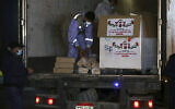 Les agents de police du Hamas montent la garde lors du déchargement d'un camion transportant 40 000 doses de vaccin russe anti-COVID-19 Sputnik V à son arrivée dans la bande de Gaza, au poste-frontière de Rafah avec l'Égypte, le 11 mars 2021. (Crédit : Adel Hana/AP)