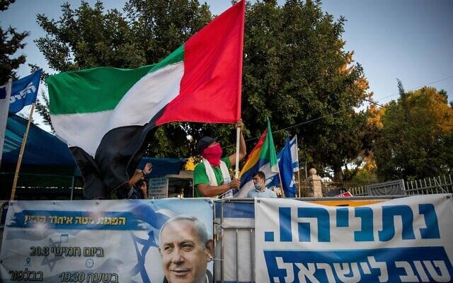Un homme brandit un drapeau émirati géant devant la résidence officielle du Premier ministre à Jérusalem, le 19 août 2020. (Crédit : Yonatan Sindel/Flash90) Un homme brandit un drapeau émirati géant devant la résidence officielle du Premier ministre à Jérusalem, le 19 août 2020. (Crédit : Yonatan Sindel/Flash90)