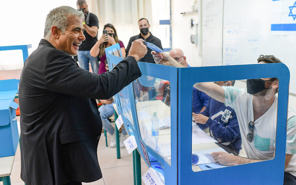 Le chef du parti Yesh Atid, Yair Lapid, et son épouse Lihi déposent leur bulletin de vote dans un bureau de vote à Tel Aviv, lors des élections pour la Knesset, le 23 mars 2021. (Tomer Neuberg/Flash90)