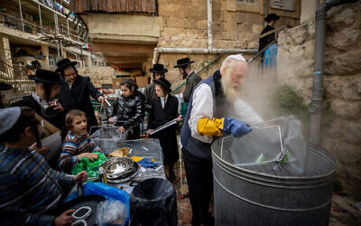 Des Juifs ultra-orthodoxes stérilisent des marmites dans l’eau bouillante pour éliminer toute trace de levain avant la prochaine fête de Pessah, dans le quartier ultra-orthodoxe de Mea Shearim à Jérusalem, le 25 mars 2021. (Yonatan Sindel / Flash90)